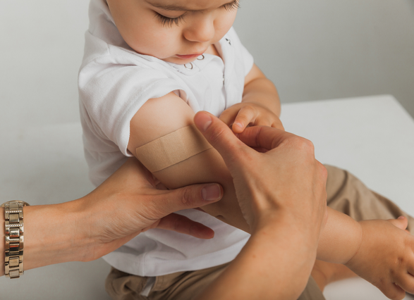 Manos pegándole una cura a un niño