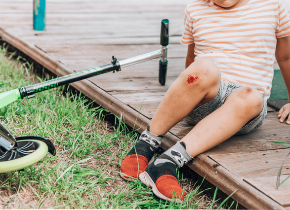 Niño sentado con raspaduras en las rodillas