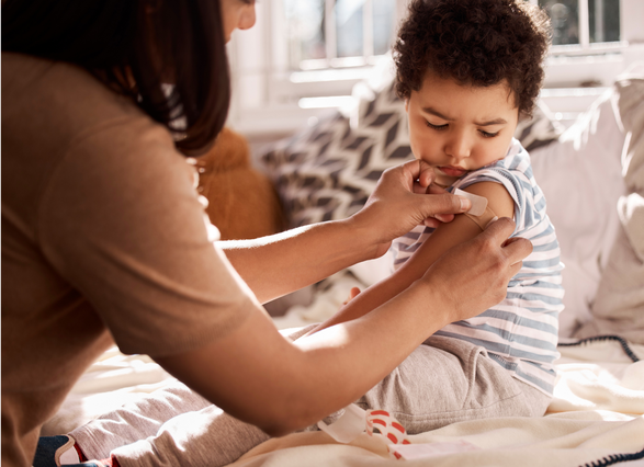 Mujer poniendo una cura en el brazo a un niño