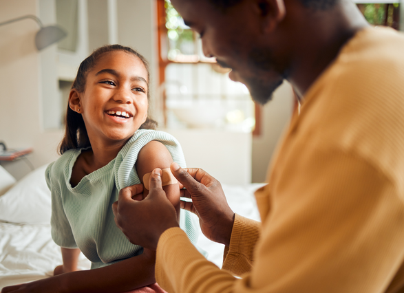 Hombre poniéndole una cura en el brazo a una niña